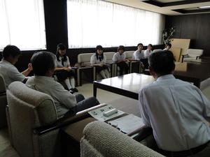 手前に関係者の男性3名、窓際の椅子に派遣学生が座っている写真
