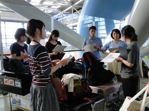 たくさんの荷物を置き、資料を見ながら説明を聞いている学生達の写真