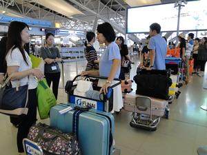 沢山の荷物をカートに乗せ出発を待っている学生達の写真
