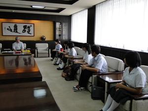 市長室の椅子に座り、市長に帰国報告をしている6名の学生の写真