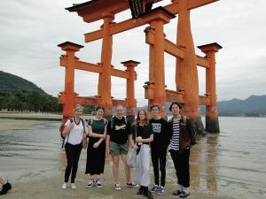 水に浸かった厳島神社の鳥居の前で記念撮影をしているリズモー市からの学生6名の写真