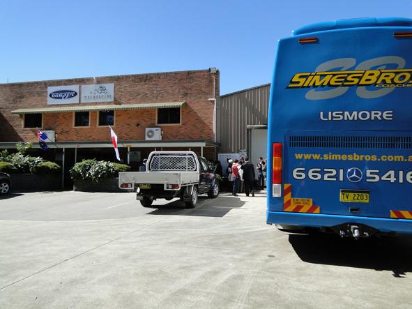 工場に停められたバスと車を後ろから写した写真