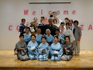 着物を着た11名の方々と扇子を持ったリズモー市の学生達、関係者達の記念撮影をしている写真