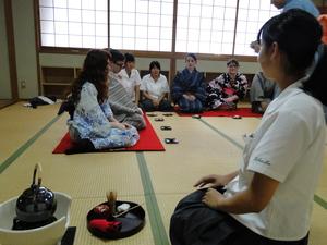 茶道の亭主の人が見守る中、浴衣姿のリズモー市の学生達の前にお菓子が配られ茶道の体験をしている写真