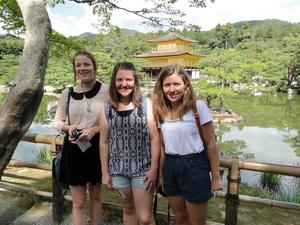 池の奥に金閣寺が見える場所でリズモー市の女子学生3人が記念撮影をしている写真