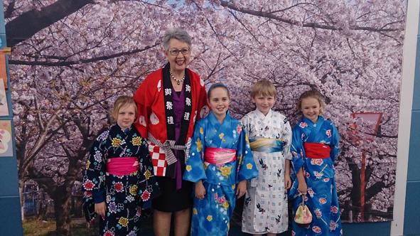 桜の絵の前で法被をきたリズモー市長と浴衣姿のオーストラリアの子供4人の写真