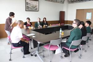 四角に並べられた机にリズモー市の学生達が座って磐園小学校の関係者の人の話を聞いている写真