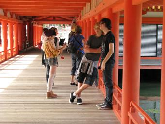 柱や、梁が朱色に塗られてある社殿を見学している外国人たちの写真