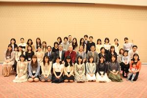 コリーンさんとリックさん夫妻が中央に座り、周りに参加者達が並んで記念撮影をしている写真