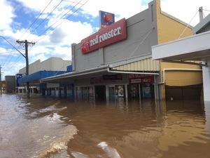「red rooster」と書かれた店の入り口半分の高さまで水で浸かっている街並みを写した写真