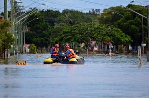 水で浸かった道路をボートで救助に出ている男性2名の写真