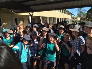 帽子を被った子供達がたくさん集まりピースをしている写真