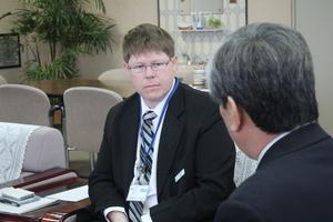 椅子に座り、真剣な面持ちで吉田市長の方を見ているキャメロンさんの写真