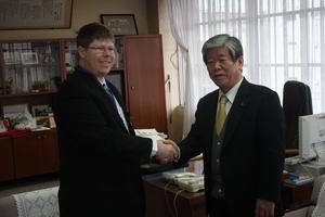 キャメロンさんと吉田市長が笑顔で握手を交わしている写真