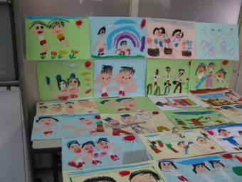 壁に貼られた絵と、机に並べられた沢山の絵の写真