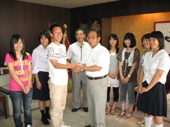 交換学生6名がが市長を表敬訪問し、男子学生が副市長と握手を交わしている写真