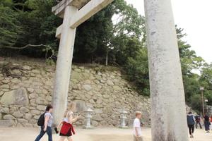 大きな鳥居の下をくぐる外国人の人達を横から写した写真
