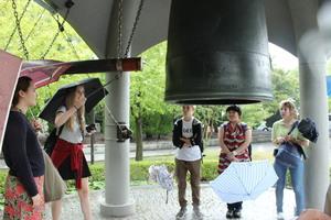 傘をさしながら鐘をついているリズモー市の学生達の写真