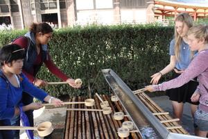 手水舎の柄杓で手を洗っているリズモー市の学生達の写真