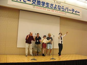舞台の上で両手を挙げたり、両手でガッツポーズをしている外国人5名の方の写真