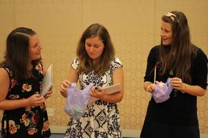 リズモー市の女子学生3人が手にノートや袋を持ち顔を見て話している様子の写真