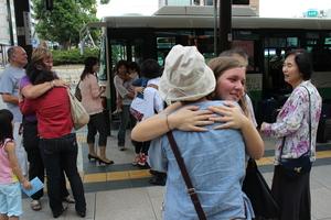 停まっているバスの前でリズモー市の女子学生と日本人の方が抱き合って別れを惜しんでいる写真