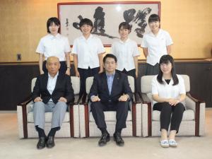 制服姿の5名の女子学生が市長室で市長と関係者2名と一緒に集合写真