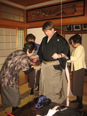 3人の女性がキャメロンさんの袴の着付けを行っている写真