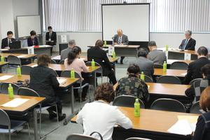前方にそれぞれ5名の方が座り、参加者達も書類に目を通している定期総会の写真