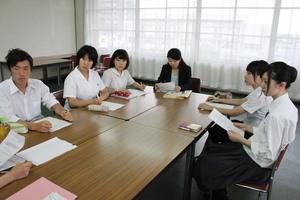 5名の学生達が真剣な顔で机に座り話を聞いている写真