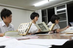3名の学生がアルバムを見ている写真
