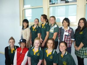 緑色の制服を着たリズモー市の学生達と一緒に並んで記念撮影をしている派遣学生の写真