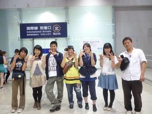 空港の到着口前で1列に並び笑顔でピースサインをしている7名の派遣学生の写真