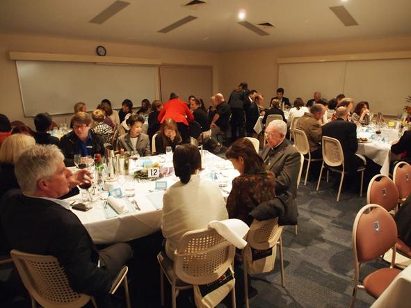 たくさんの人達がテーブルに座り食事会を楽しんでいる写真
