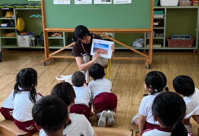 子どもたちに女性が写真を見せながら指差しているところ