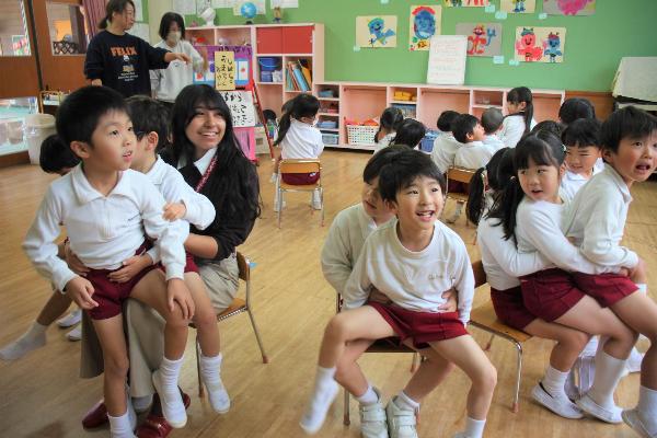 仲良し椅子取りゲームをやっている大人数の園児たちと1人の女性の様子
