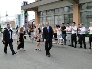 市役所職員が拍手で出迎える中、道路中央を歩いている外国人4名の写真