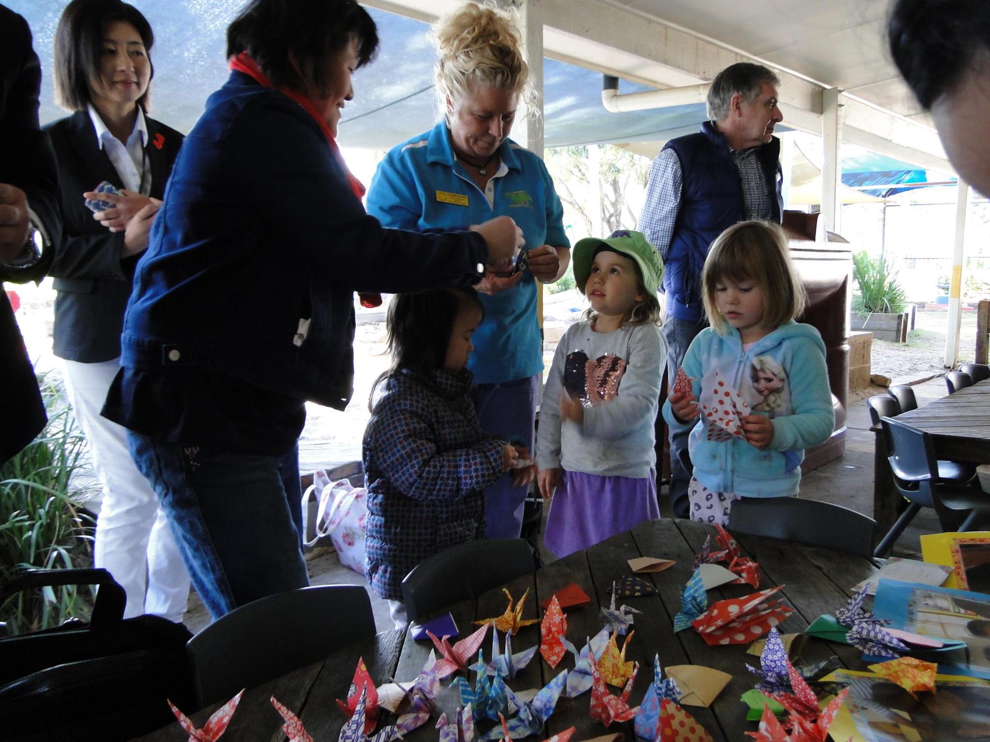 机に並べられた折鶴をもらっている子供たちの写真