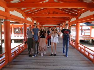 厳島神社の拝殿内を歩いて見学しているリズモー市の学生5名と先生の写真