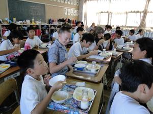 小学生と一緒に給食を食べているリズモー市の学生の写真