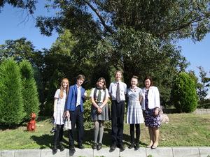 緑の木々の前で記念撮影をしているリズモー市の学生5名と引率の先生の写真