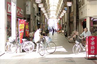 片塩商店街のアーケードを自転車で通行している人達の写真