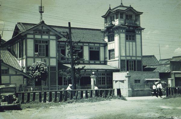 2階建ての白い外壁で、窓枠がレトロな昔の大和高田市警察署の建物全体を写した白黒写真