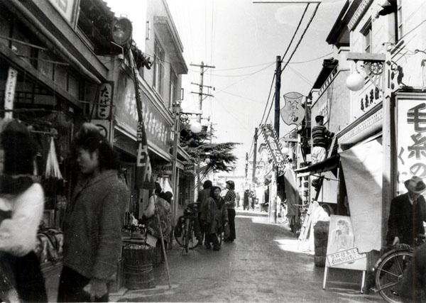 アーケードがまだない昔の天神橋筋商店街で買い物をしている人達を写した白黒写真