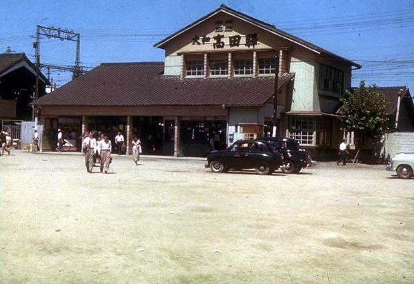 茶色の三角屋根の昔の近鉄大和高田駅の建物から下車する人達を写した写真