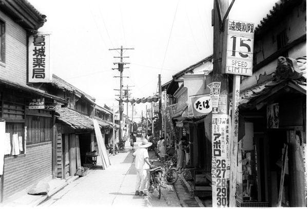 葛城薬局の看板が左側店舗にある本町商店街南側の入り口の白黒写真