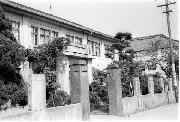 昔の片塩小学校の校門と校舎を斜めから写した白黒写真