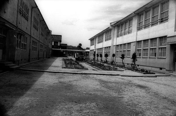 校舎と校舎の間に広い空き地がある片塩小学校の白黒写真