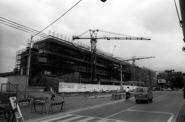 横断歩道奥に4階建ての建物の建設工事中の白黒写真