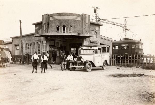 高田町駅前の道路に停車している車と行き交う人たちを写した白黒写真